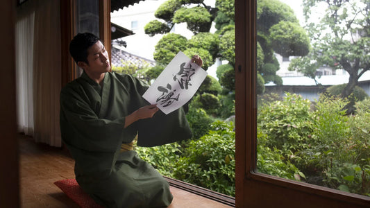 Homme japonais en kimono pratiquant la calligraphie traditionnelle avec un caractère japonais signifiant "santé et rêve", symbole de sagesse et de culture japonaise.