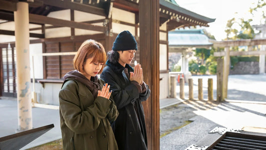 Deux jeunes japonais en prière dans un temple shinto, illustrant la spiritualité et les traditions religieuses du Japon.