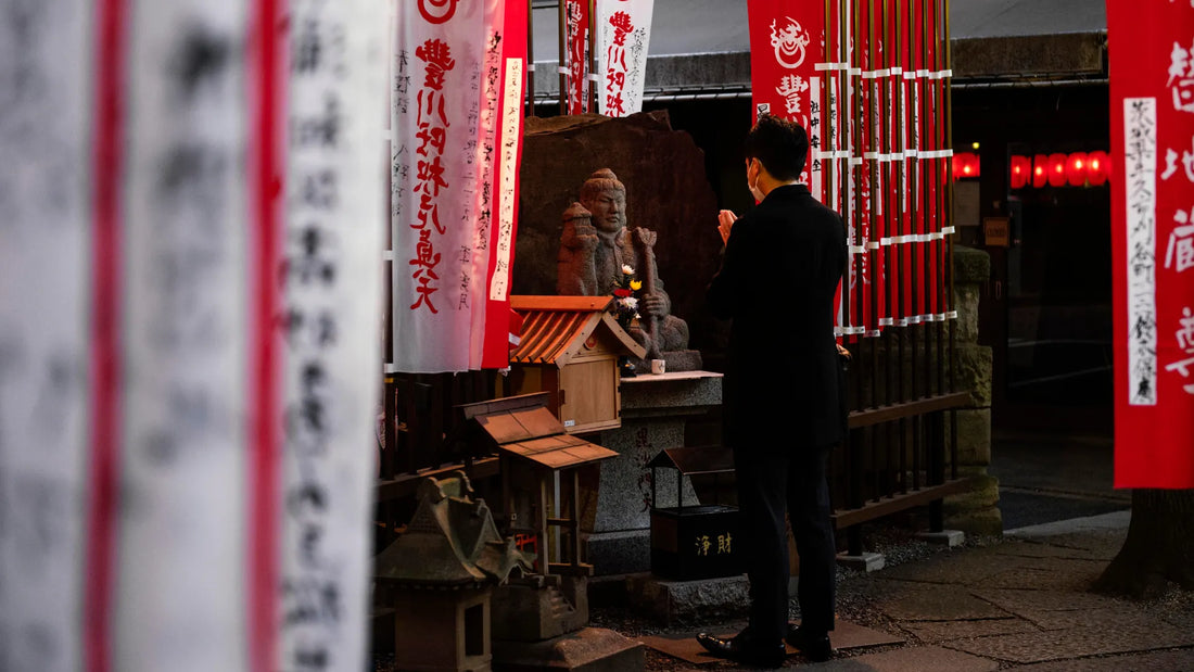 Un salaryman en costard moderne qui prie devant un petit autel traditionnel