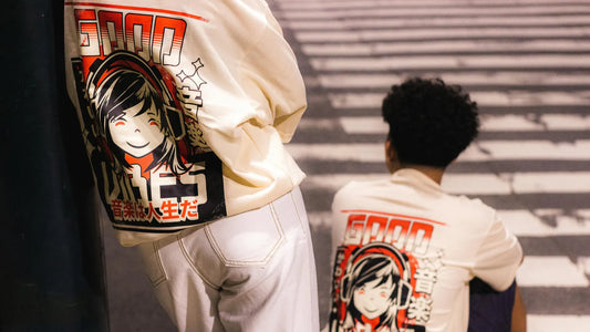 Deux jeunes portant un sweat manga blanc avec un design graphique coloré dans une rue urbaine de nuit.